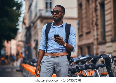 Handsome American Tourist Is Checkin His Mobile Phone On The Busy Street In The City.