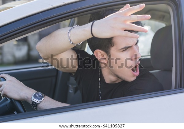 Handsome Angry Young Man Driving a Car and Yelling to\
someone in front of\
him