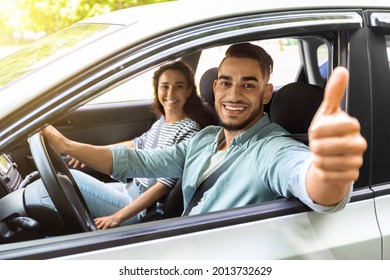 Handsome Arab Guy Sitting Inside Car With Gilfriend And Showing Thumb Up, Smiling At Camera. Happy Middle-eastern Couple Or Family Renting Auto For Their Weekend Trip, Going Vacation Together