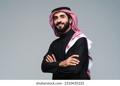 Handsome arab middle-eastern saudi arabian man with traditional saudi clothing in studio - Arabic muslim adult male businessman wearing thwab portrait isolated on gray background