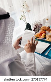 Handsome Arabian Male Using Digital Tablet During Breakfast