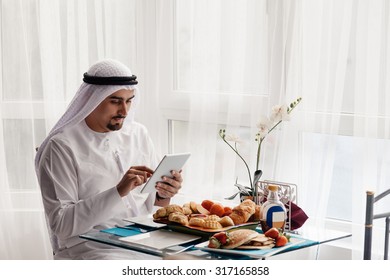 Handsome Arabian Male Using Digital Tablet During Breakfast