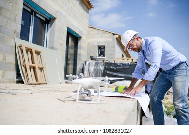 handsome architect flying inspection drone for aerial view of a house construction site industry