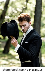 handsome aristocratic man holding hat while standing in suit 