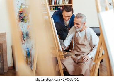 Handsome Artist Helping Elderly Man In Painting