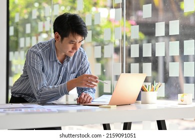 Handsome Asian Businessman In Casual Blue Shirt Use Stylus Pen Point At The Laptop.