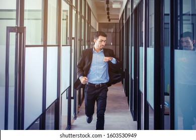 Handsome Asian Businessman Checking His Watch While Running On The Office Hallway