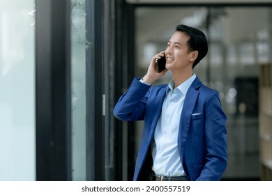 Handsome Asian Businessman Talking on Phone in Modern Office. Corporate Communication and Technology Concept. - Powered by Shutterstock