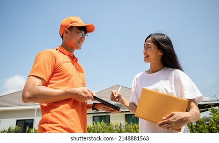 Handsome Asian Delivery Man In An Orange Uniform Holds A Tablet For Customers To Sign For An Online Order. Domestic And International Transport And Logistics