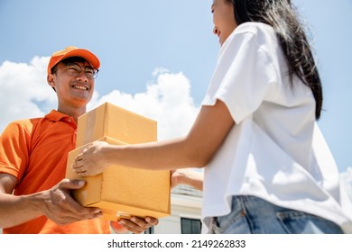 Handsome Asian Delivery Man In An Orange Uniform Holds A Tablet For Customers To Sign For An Online Order. Domestic And International Transport And Logistics