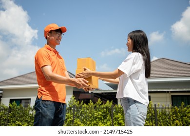 Handsome Asian Delivery Man In An Orange Uniform Holds A Unpacked Box For Customers To Sign For An Online Order. Domestic And International Transport And Logistics