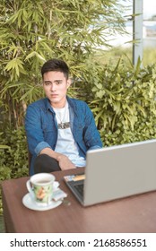 A Handsome Asian Male Freelancer With His Laptop And A Cup Of Coffee At An Al Fresco Outdoor Cafe. Modern Young Professional Working Remotely.