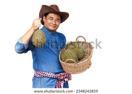  Handsome Asian man farmer wears hat, blue shirt, holds basket of durian fruits ,feels confident. Concept, agriculture occupation. Thai farmers grow durian fruits as economic and export crop          