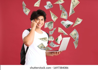 Handsome Asian man with laptop and flying money on color background