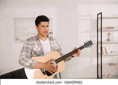 Handsome Asian Man Playing Acoustic Guitar And Singing At Home