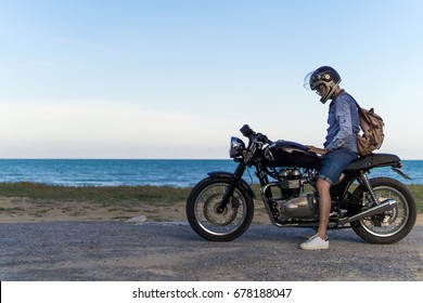 A handsome asian man is riding  motorcycle  with feeling alone on the beach. copy space - Powered by Shutterstock