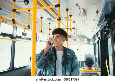 Handsome Asian Man Standing In City Bus And Talking On Mobile Phone