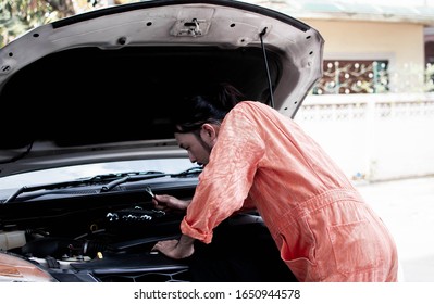 A Handsome Asian Mechanic Wearing Safety Suit Is Reparing Car Systems In Automobile Maintenance Service Center