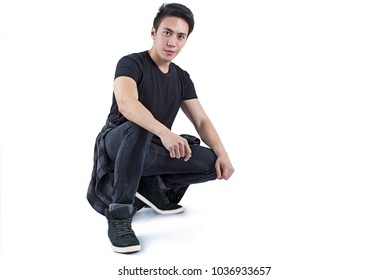 Handsome asian model in squatting position over a white background.