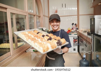 Handsome Asian Smiling Worker At The Bakery Shop Holding A Tray Of Bread