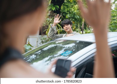 Handsome Asian Thai Man Waving Hand To Say Goodbye To His Girlfriend Before Driving A Car Back Home.