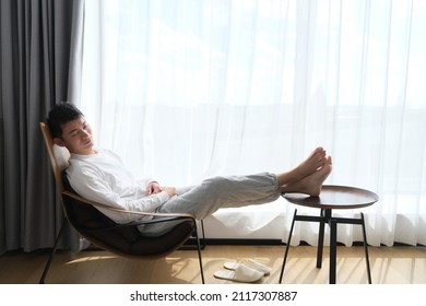 Handsome Asian Young Man Napping On Chair Near Window Under Sunshine