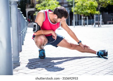 Handsome athlete doing leg stretching on the floor on a sunny day - Powered by Shutterstock