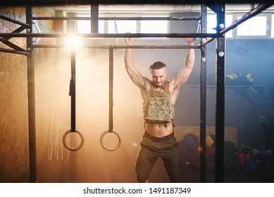 Handsome athlete man with a heavy waistcoat on his torso makes pull-ups on crossbar during training in the modern gym. Motivation concept. - Powered by Shutterstock