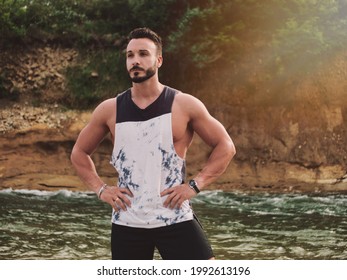 Handsome athletic young man near river, standing
