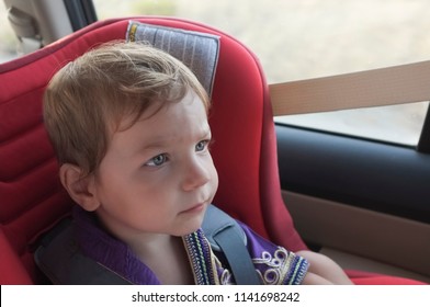 Handsome Attentitive Baby Boy In Child Car Seat. He Is Watching Toons With Tablet On Headrest