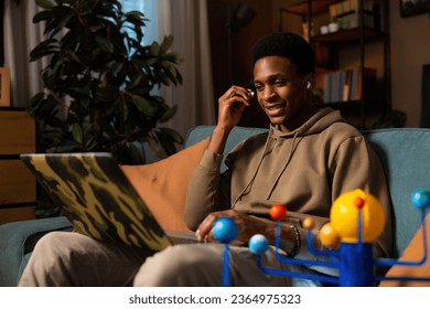 Handsome attractive African American male playing a video game, using the headphones to hear game sounds and communicate with other players online listening to music help him concentrate. - Shutterstock ID 2364975323