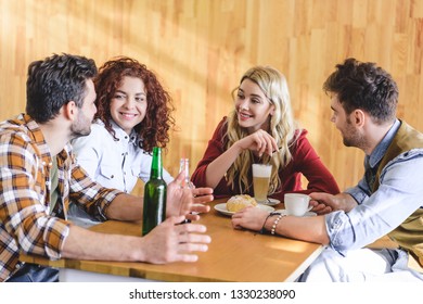 handsome and attractive friends talking and smiling at cafe 