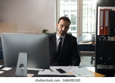 Handsome attractive man sitting on chair in front of computer indoors. Business concept - Shutterstock ID 1686985183