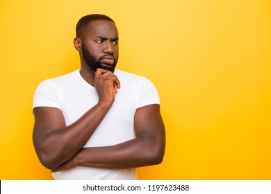 Handsome attractive manly sportive guy in white t-shirt thinking, looking aside, copy-space, isolated over bright vivid yellow background