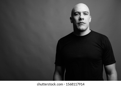 Handsome Bald Man Against Gray Background In Black And White