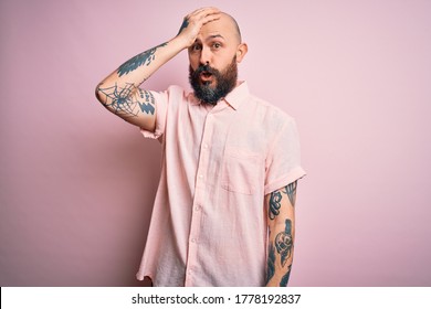 Handsome Bald Man With Beard And Tattoo Wearing Casual Shirt Over Isolated Pink Background Surprised With Hand On Head For Mistake, Remember Error. Forgot, Bad Memory Concept.
