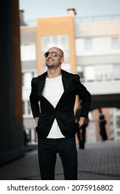 Handsome Bald Man Enjoys A Walk Around The City. A Smiling Young Man In Casual Clothes Walking Down A City Street.