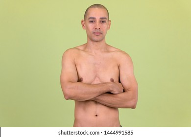 Handsome bald multi ethnic man with arms crossed shirtless