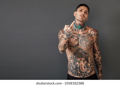 Handsome bare-chested tattooed man portrait giving the middle finger