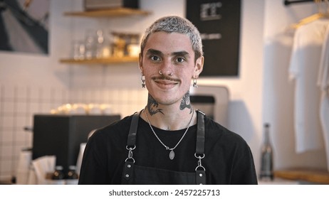 Handsome barista guy work coffee shop. Tattooed hipster man portrait. Happy male face smile. Joy young adult person look camera at cozy cafe house. Stylish dyed hair waiter make hot tasty drink order. - Powered by Shutterstock