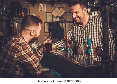 Handsome Bartender Pouring A Pint Of Beer To Customer In A Pub.