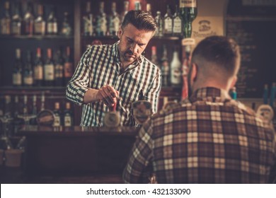 Handsome Bartender Pouring A Pint Of Beer To Customer In A Pub.