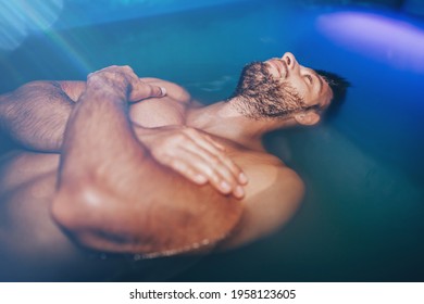 Handsome Beard Man Floating In Tank Filled With Dense Salt Water Used In Meditation, Therapy, And Alternative Medicine. 