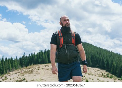 Handsome Bearded Caucasian Male 30 Y.o With A Backpack Looking At The Forest And Mountains. Hiker Travels In The Mountains On A Sunny Day.