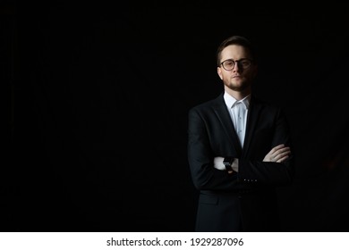 Handsome bearded confident businessman wearing black suit standing isolated over black background with arms folded. Copy space. 