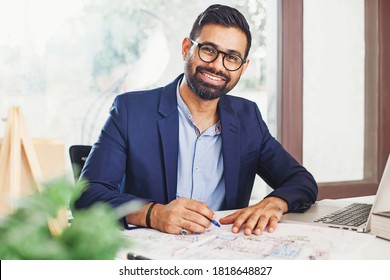 Handsome Bearded Indian Architect Working From Home On A Building Blueprint And Laptop