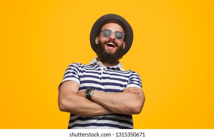 Handsome bearded male in trendy outfit keeping arms crossed and laughing while standing on bright yellow background - Shutterstock ID 1315350671