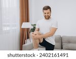 Handsome bearded man doing hamstring stretch exercise at home.
