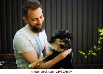 Handsome Bearded Man Embracing His Dog In Park.