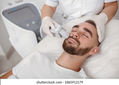 Handsome Bearded Man Getting Facial Laser Treatment By Cosmetician